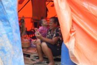 Seorang ibu dan anak memanfaatkan layanan telekomunikasi pascabencana di Sumatra. Foto:Telkom