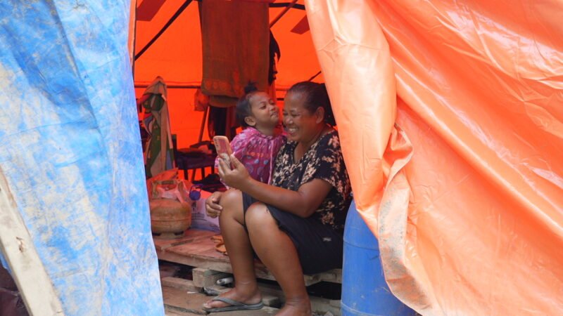Seorang ibu dan anak memanfaatkan layanan telekomunikasi pascabencana di Sumatra. Foto:Telkom